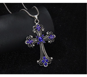 Detail of silver stainless steel cross pendant featuring faceted blue crystals