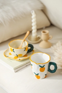 Detailed view of hand-painted ceramic coffee cup with orange pattern and wavy rim