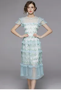 Détail de broderies florales bleu clair sur une robe romantique en tulle