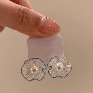 Macro shot of silver flower earrings with radiant petal texture and centered white pearl