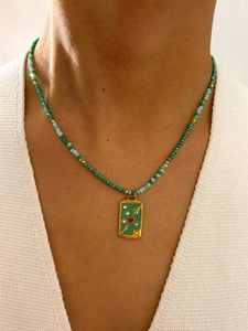 Gros plan du collier de perles bohème avec pendentif carré émaillé vert et détail de cœur rouge