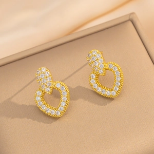Nahaufnahme goldener Herzohrringe mit Zirkonia-Mikropavé auf Seidenhintergrund
