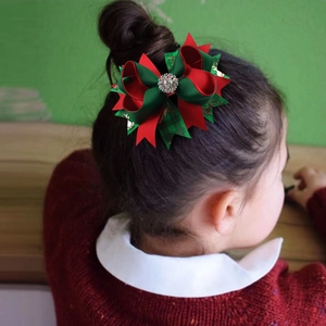 Close-up of a Christmas bow hair clip with gold reindeer patterns on a young girl hair