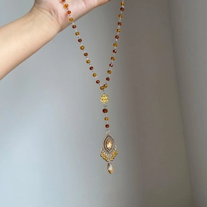 Détail de perles en cristal ambre et pendentif en bronze gravé avec gemme jaune