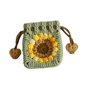 Handmade crochet sunflower drawstring pouch in green yarn with heart-shaped tassel accents