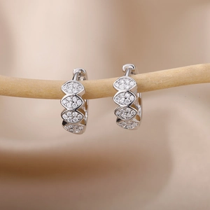 Close-up of silver C-shaped hoop earrings with marquise-cut pavé zircon on a wooden branch