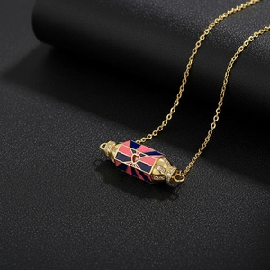 Macro shot of gold necklace with colorful cylinder pendant and sparkling zircon details