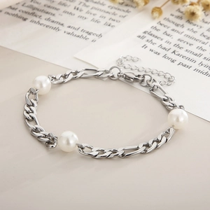 Macro shot of silver titanium bracelet featuring three white pearls and lobster clasp