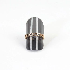 Detail of a golden chain-link ring showcased on a gray cone-shaped display stand