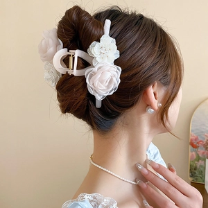 Side view of a floral hair claw clip with cream pearls on an elegant updo hairstyle