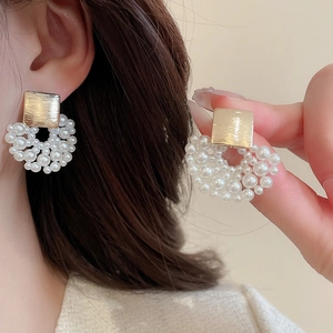 Detailed view of luxury square gold metal studs with elegant white pearl cluster drops