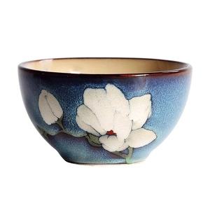 Japanese ceramic rice bowl with blue glaze and white magnolia floral pattern on white background