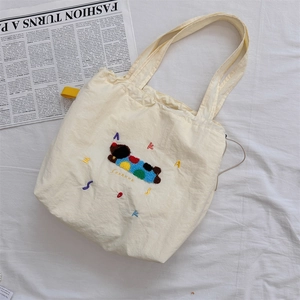 Detailed embroidery of a cute cartoon dog and colorful letters on a cream canvas tote bag