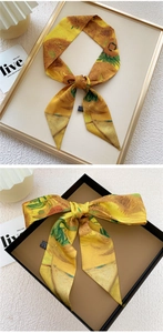 Detail of sunflower oil painting style twilly silk scarf tied on a dark gift box