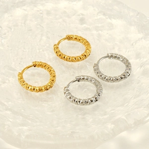 Detail of gold and silver hoop earrings featuring a diamond-cut textured pattern