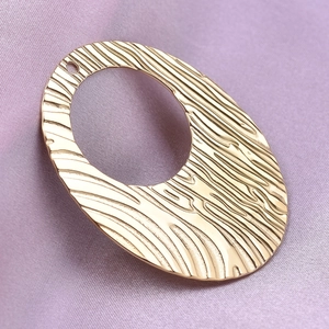 Gold 304 stainless steel oval pendant with wood grain texture on purple fabric background