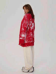Detail of red and white knitted cardigan featuring distressed hem and textured yarn