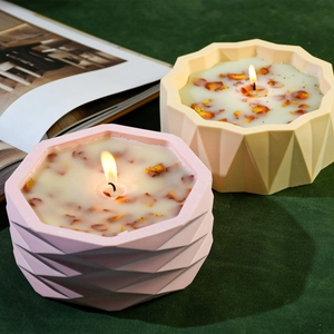 Detail of geometric scented candles with dried flower petals on green velvet