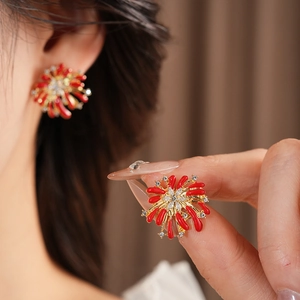 Detail of gold flower earrings with red accents and sparkling crystals on model ear