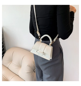 Close-up of minimalist cream white cross body bag featuring premium litchi grain leather