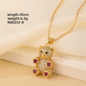 Detail shot of a gold teddy bear pendant with white zircons and red heart gems