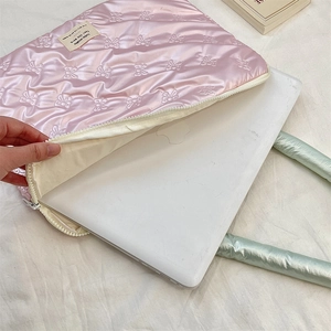 Detail of pink quilted laptop sleeve with bow texture showing soft white inner lining