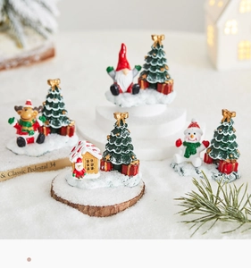 Detailed view of miniature Christmas resin ornaments with snowman and santa on faux snow