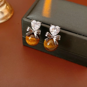 Detail of zircon heart earrings with silver bow and tiger eye stone bead charms