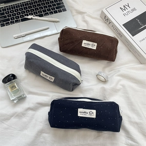 Detailed view of polka dot fabric pencil cases in brown, grey, and navy blue wool