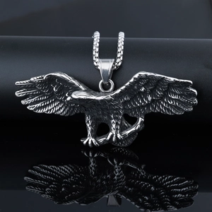 Polished stainless steel eagle pendant with wings spread reflecting on dark surface