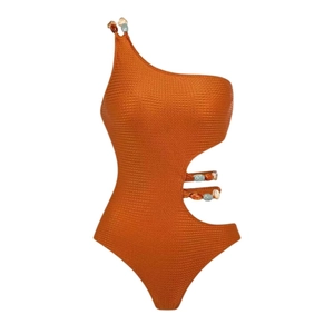 Detail of one-shoulder brick red swimsuit featuring honeycomb texture and bead accents