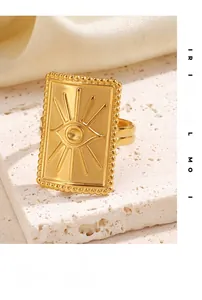 Vue détaillée d'une bague rectangulaire dorée avec relief de soleil sur surface en pierre
