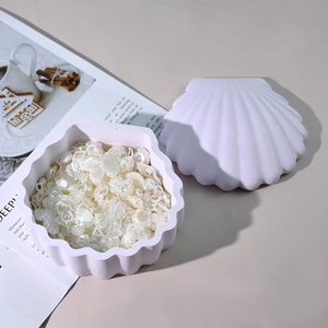 Detalle de caja de resina en forma de concha con elegantes accesorios de joyería y perlas
