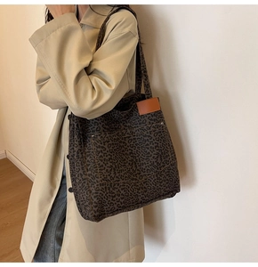 Detail of leopard print canvas tote bag featuring brown leather patch and shoulder straps