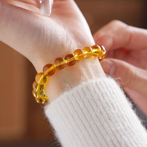 Close-up of translucent citrine crystal bead bracelet worn on wrist with soft white knit