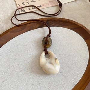 Macro view of vintage marbled stone pendant with tassel on rustic calligraphy paper