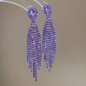 Macro shot of purple teardrop crystal fringe earrings on a U-shaped display stand