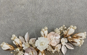 Detail of bridal hair comb with ceramic flowers, pearls, and golden leaves on velvet
