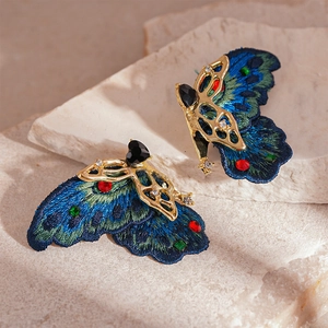 Gros plan détaillé des boucles d'oreilles papillon brodées avec cristaux sur pierre
