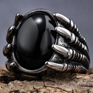 Gothic punk dragon claw ring with large oval black gemstone on rustic wood surface