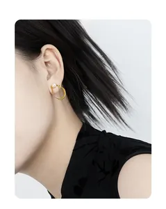 Close-up of elegant gold oval hollow earrings with white pearl inlay on a model