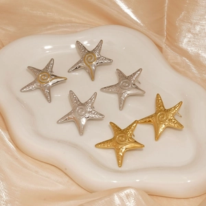 Nautical starfish stud earrings in gold and silver finish on silk fabric background
