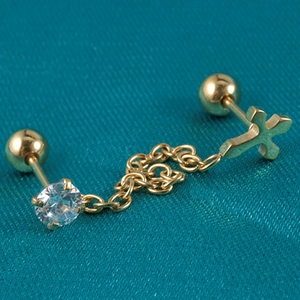 Macro shot of gold cross pendant earring with cubic zirconia and delicate chain link