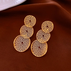 Detail shot of golden triple-tier circular drop earrings with intricate hollow mesh pattern