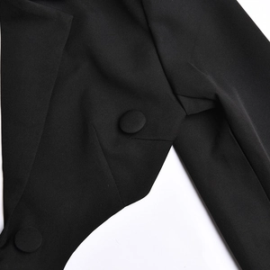 Detail shot of the black fabric texture, peak lapel, and cloth-covered buttons of the dress