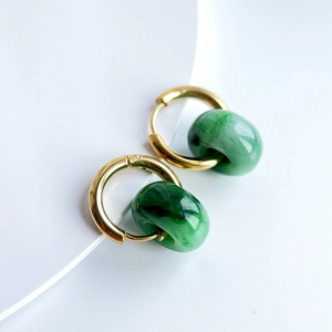 Close-up of gold-plated stainless steel hoop earrings with green stone texture pendants