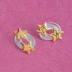 Détail de boucles d'oreilles étoiles dorées sur base argentée et tissu rose