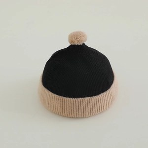 Detail of baby knit beanie with pompom showing ribbed texture and rolled brim