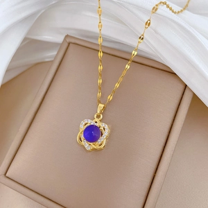Detailed close-up of a gold necklace with a blue gemstone heart pendant on a jewelry box