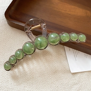 Detail of resin hair claw clip with green cat eye beads and transparent brown acrylic frame